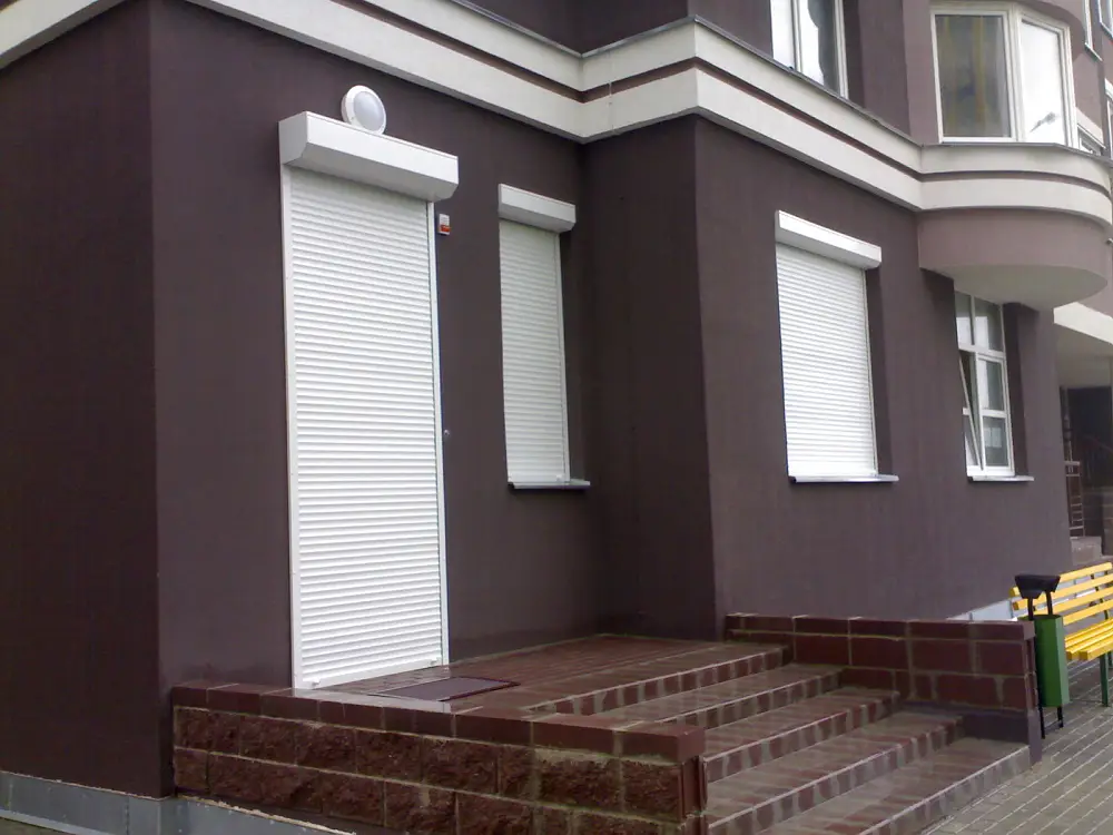 Классические белые рольставни, установленные на окнах и двери в офисе в центре города